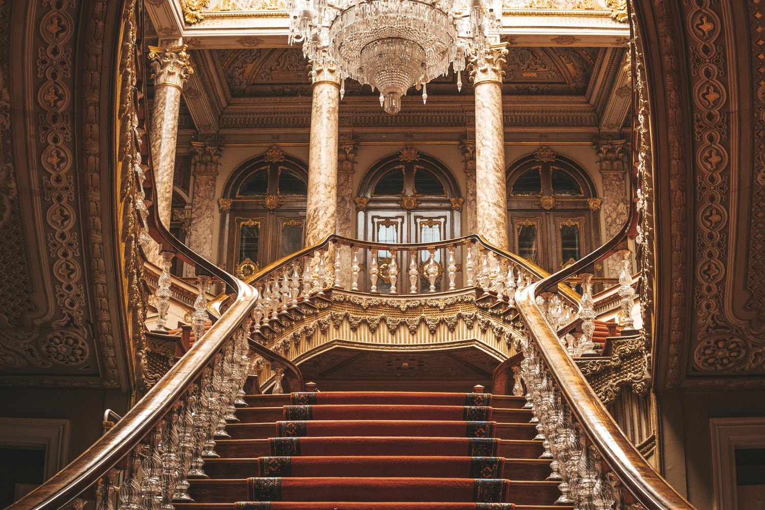 Inside of the Dolmabahçe Palace, stairs with red carpets and shiny trailing