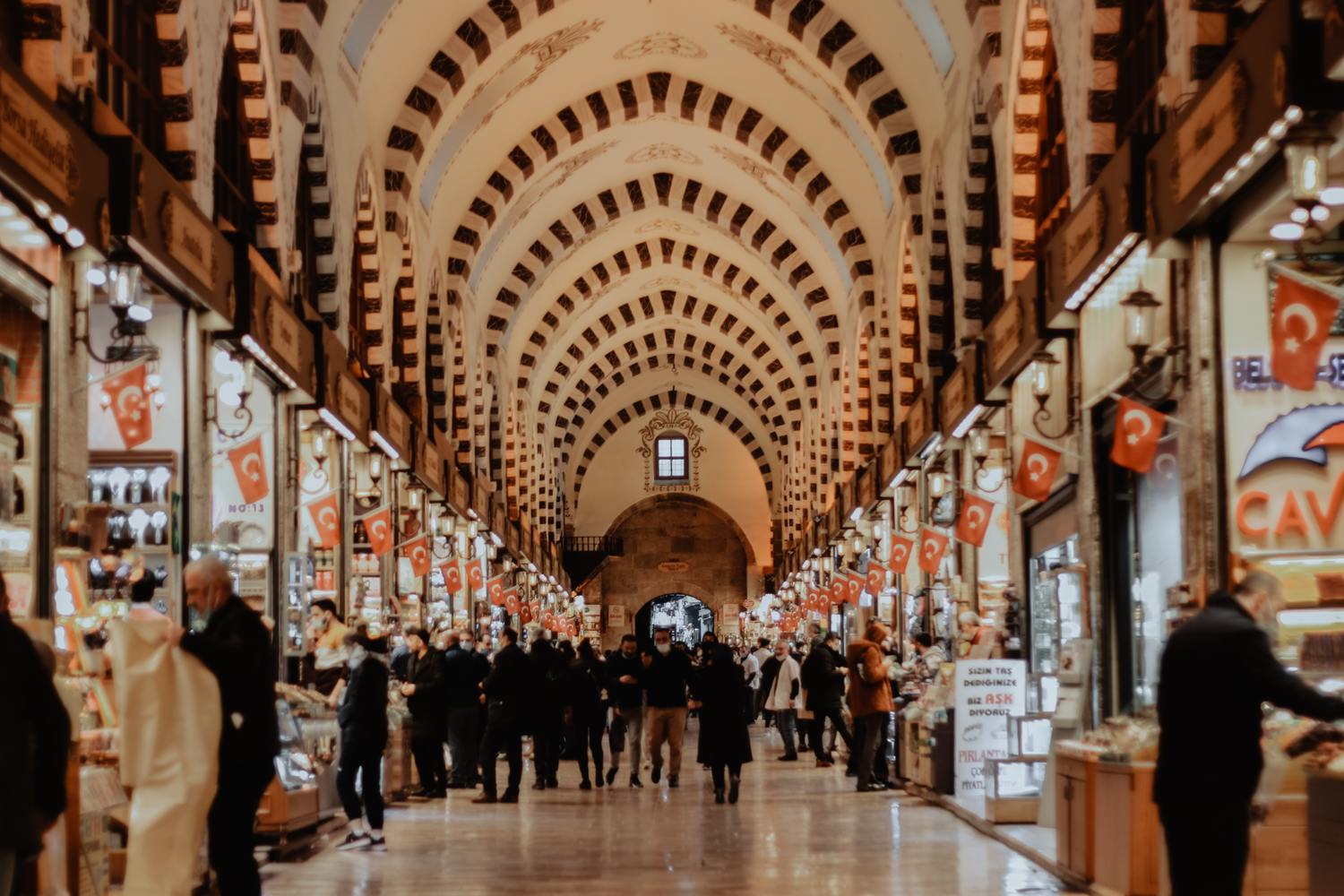 Interior of the grand bazaar, people are shopping and Turkish flags are hanging from every store entrance